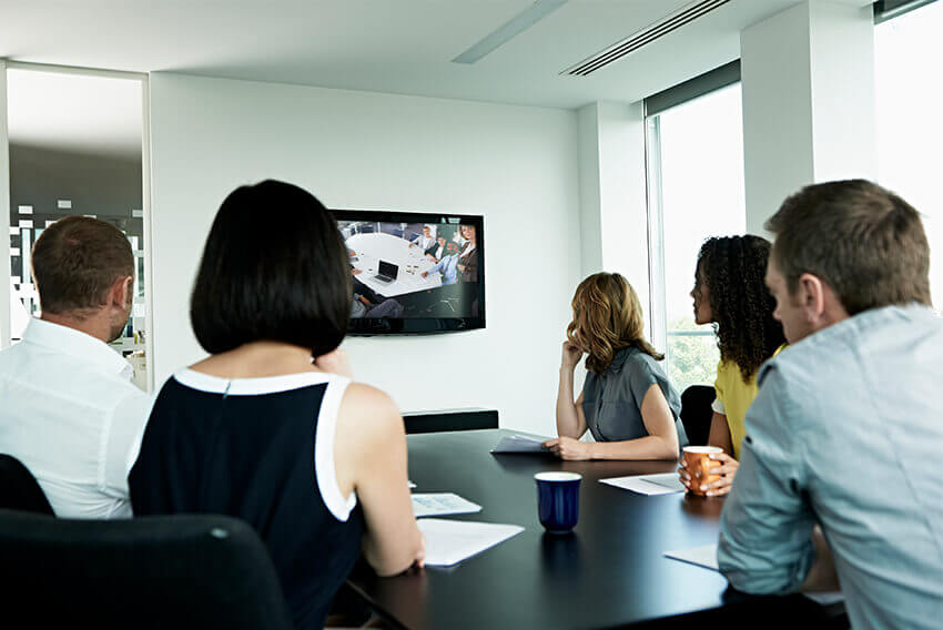 Five individuals in a conference room viewing a TV display.  Aston Carter Recruitment Articles.