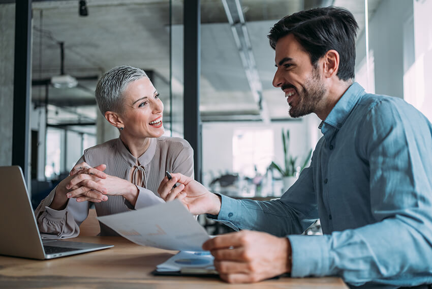 Male and female coworkers discussing how business transformations change how a company operates and require staffing solutions to help implement and sustain a company’s transformation initiatives.