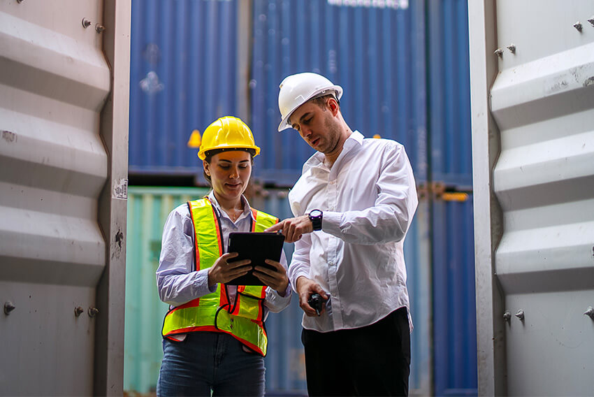 Male and female supply chain professionals onsite discussing how contract talent can help procurement teams adapt to the impact of tariffs on supply chains with urgency.