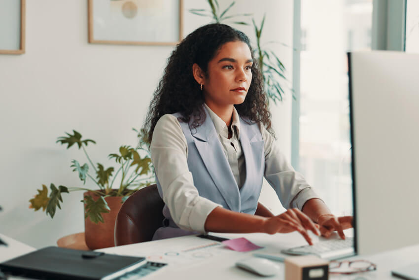 Female professional at a computer learning how to leverage HRIS strategy and HR automation for long-term growth.