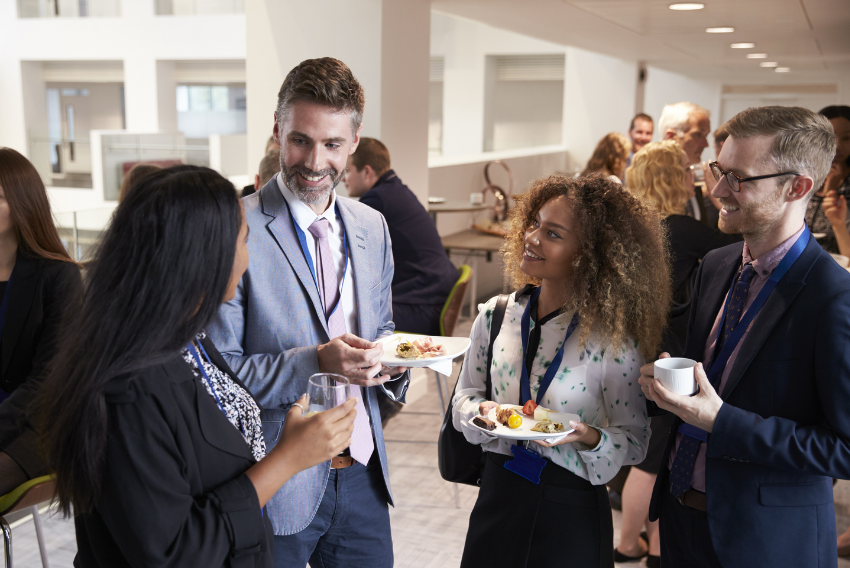 two men and two women carrying food and networking