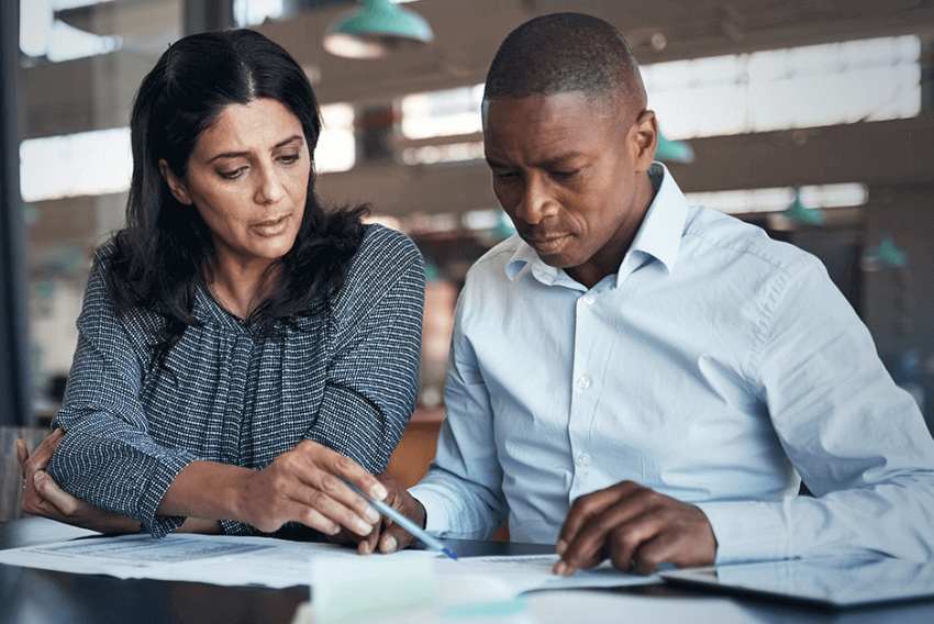 A woman showing her male coworker the governance, risk and compliance (GRC) trends for 2023.