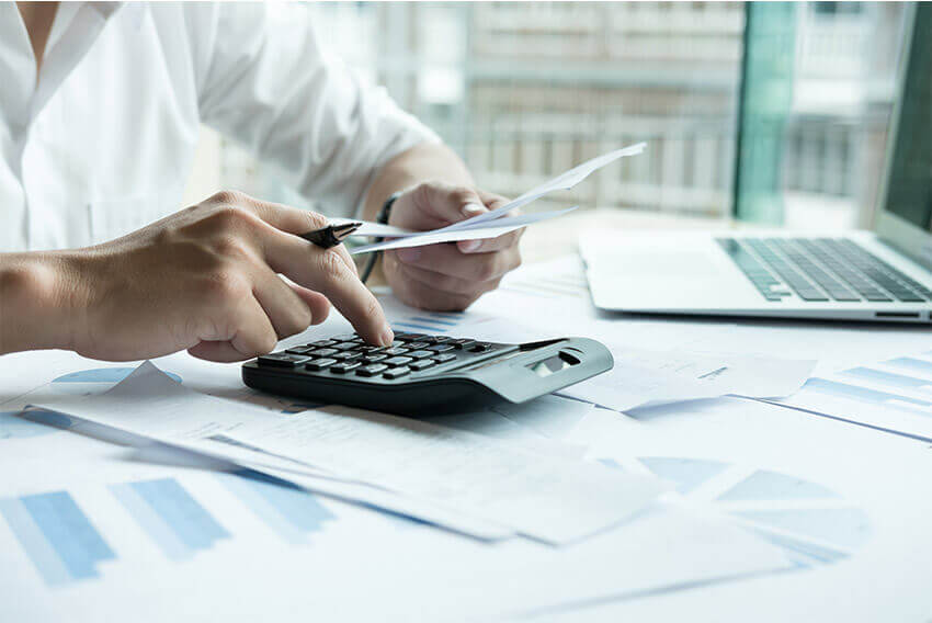 Individual using a calculator, holding a paper. Aston Carter Staffing Articles.