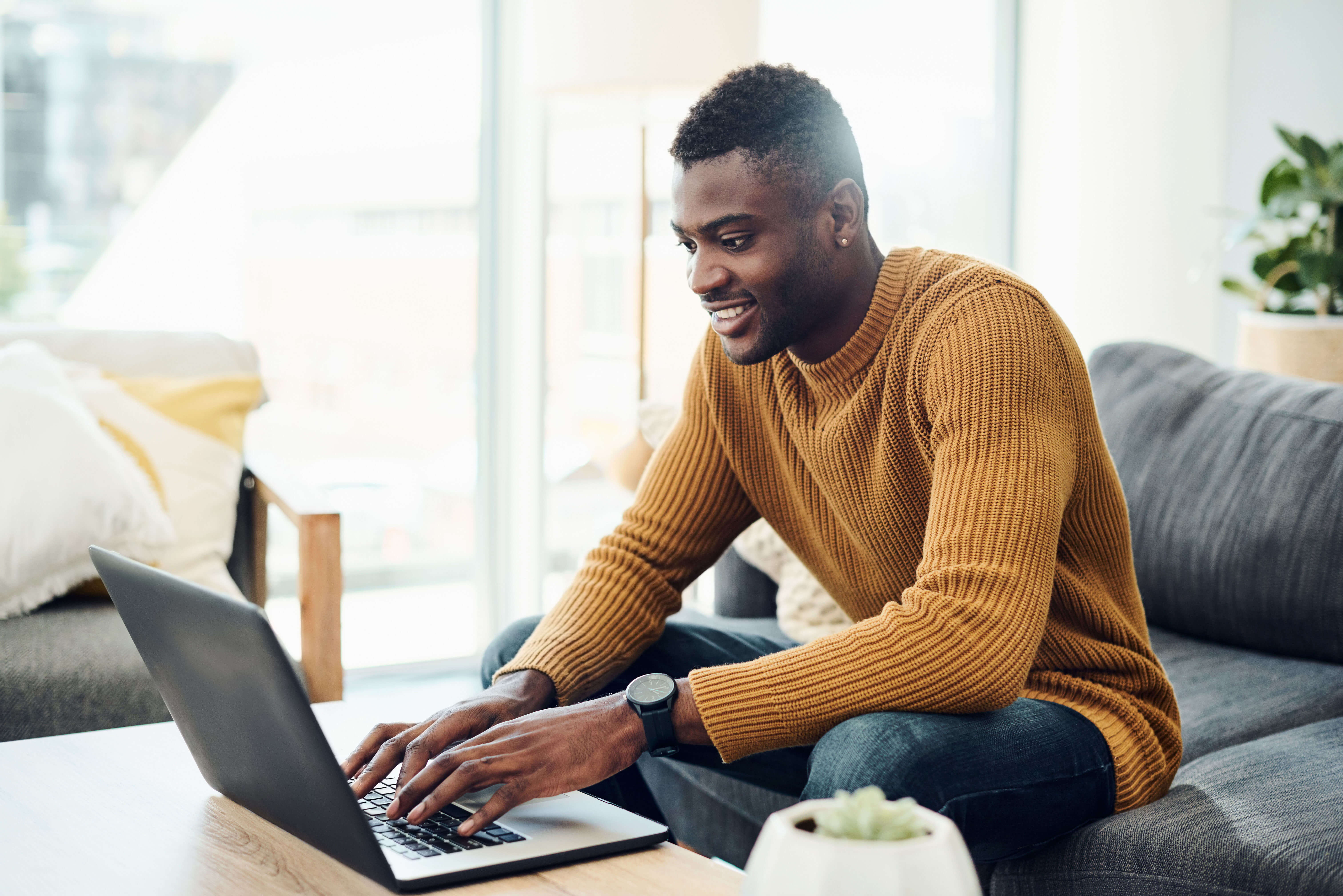 A male employee proving his value while working remotely on his laptop.