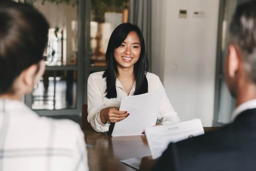 Young woman smiling at an interview holding a resume