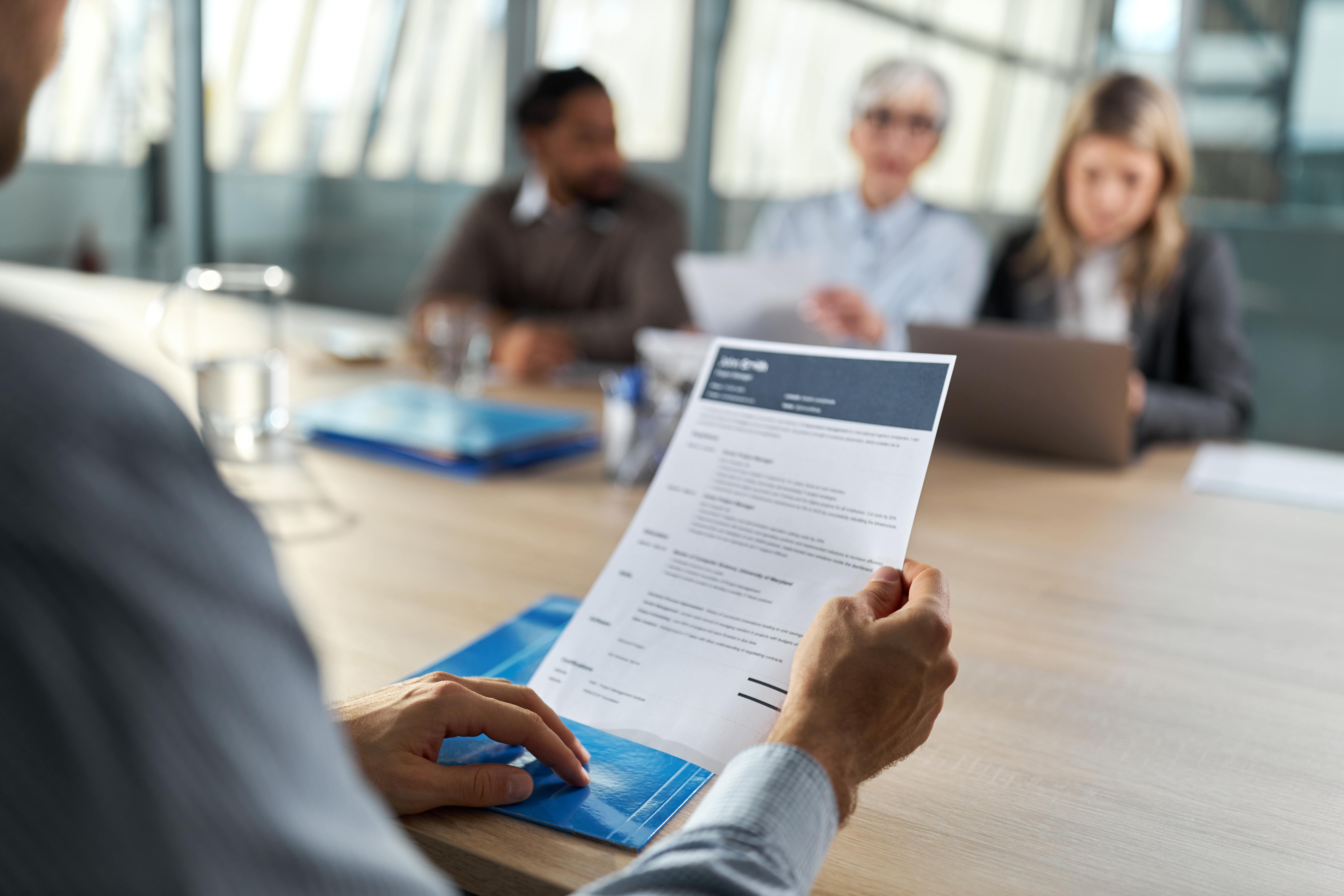 A man and a group of women reviewing resumes.