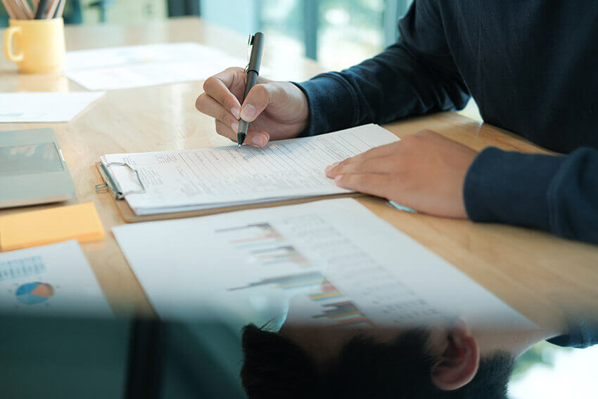 Professional sitting at a desk writing and preparing reports. 