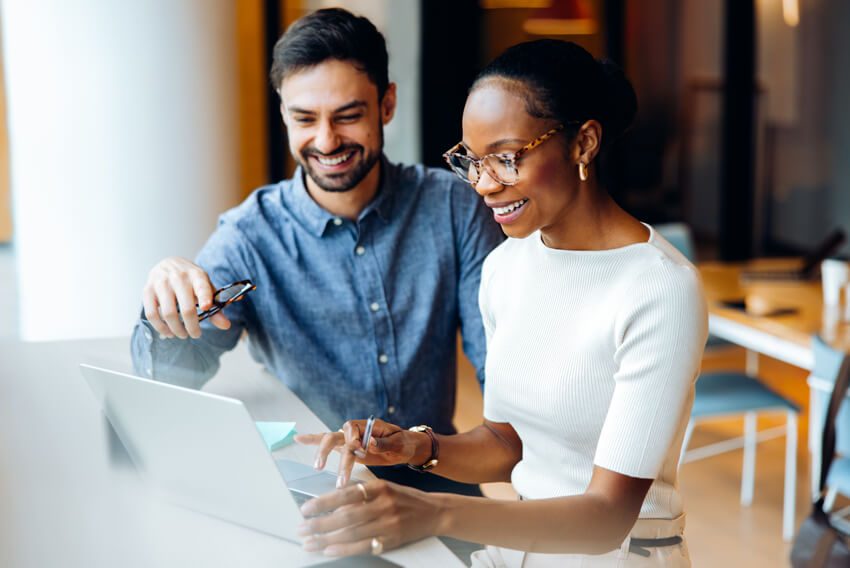 Male and female coworkers reviewing the August 2026 jobs report on a laptop looking at July 2026 labor market and economy trends.
