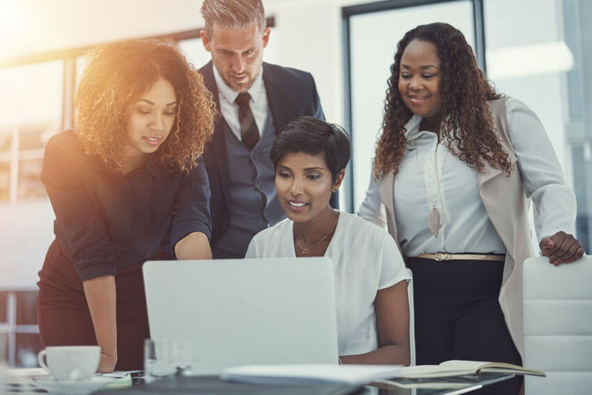 A group of coworkers reviewing the March 2024 jobs report on a laptop.