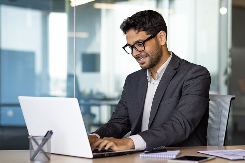 Male professional reviewing the March 2026 jobs report on a laptop looking at February labor market and economy trends.