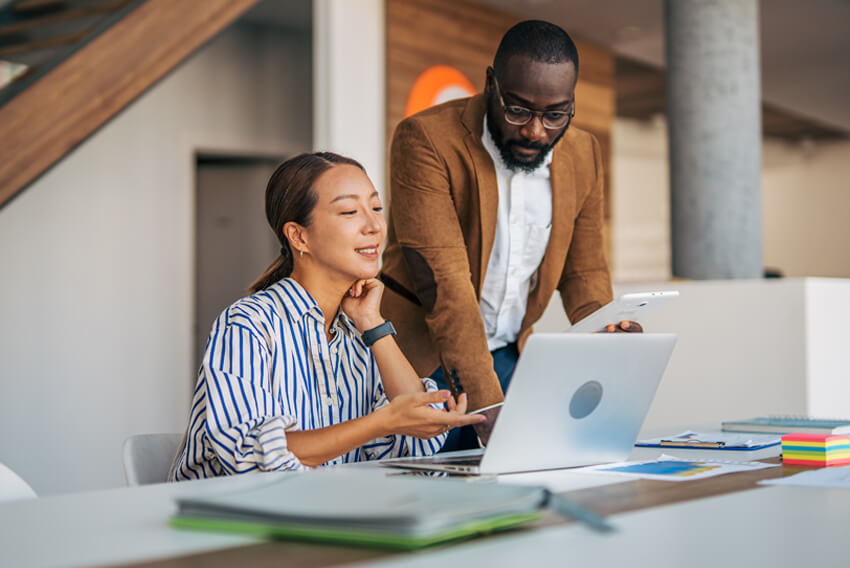 Male and female professionals reviewing the September 2026 jobs report on a laptop looking at August 2026 labor market and economy trends.