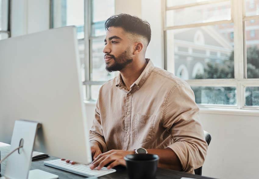 A man reading the February 2023 jobs report on his computer.