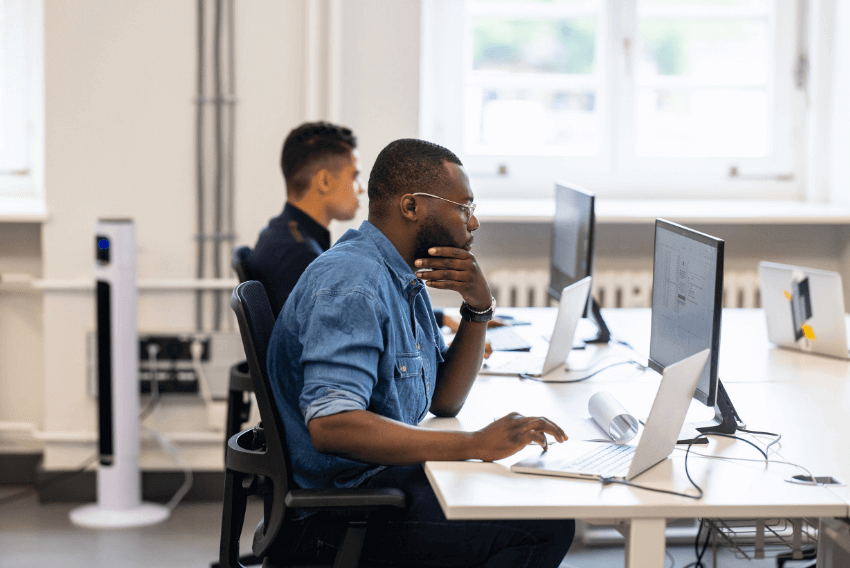 Two men reading the October 2023 jobs report in the office.