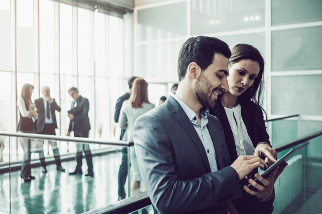 Two professionals looking at a tablet and while chatting. 